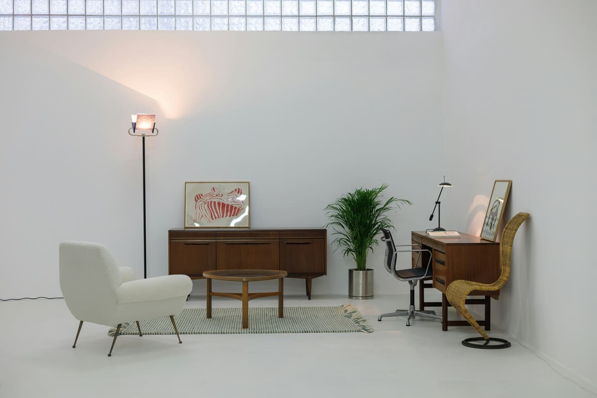 A white armchair and mid-century sideboard in a bright room with generous negative space.