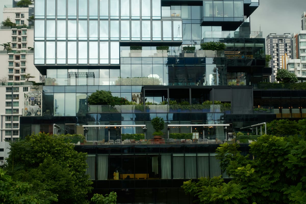 A glass residential facade with integrated planted terraces layered against the city.